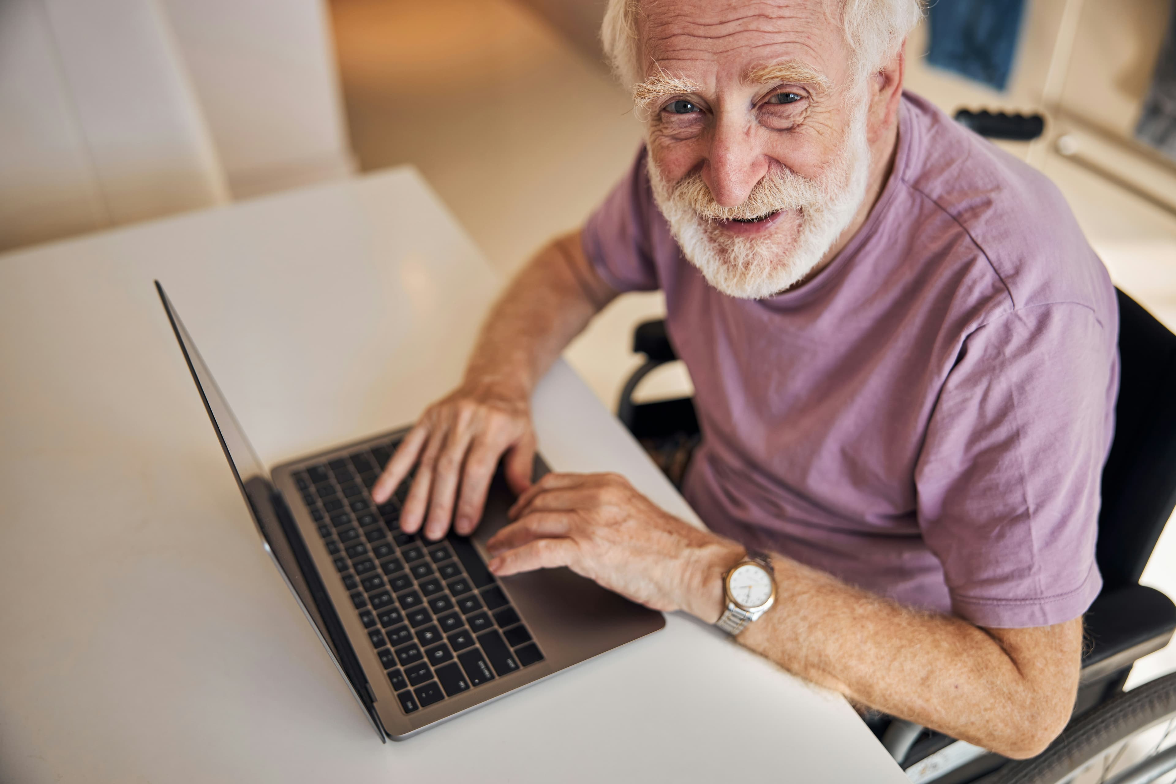 A warm, inviting photo of an older adult happily reading emails on a laptop, symbolizing seniors staying connected online.
